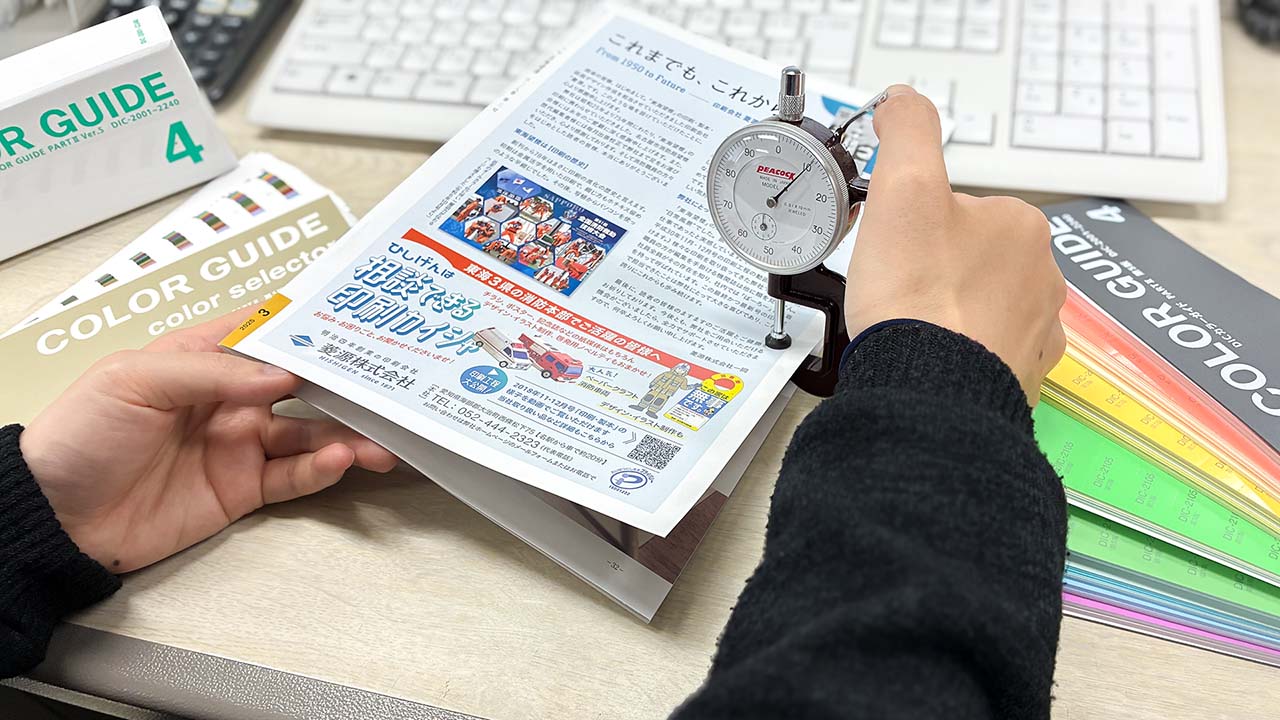 印刷会社 菱源の営業部(紙厚計を使って用紙の厚さを確認しているところ)