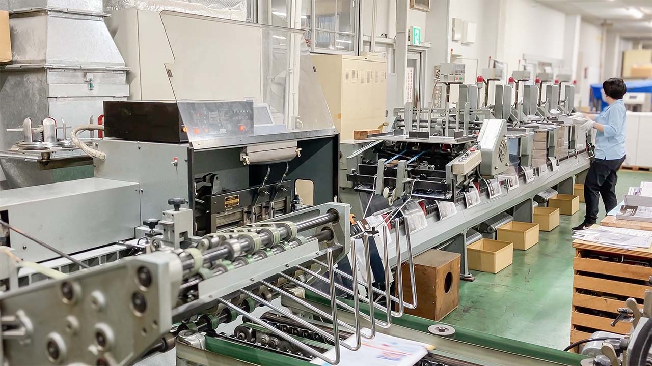 印刷会社 菱源の製本課、製本オペレーターによる冊子の中綴じ工程